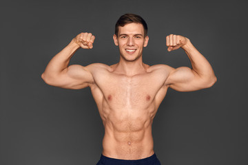 Fototapeta premium Young sportsman showing muscles