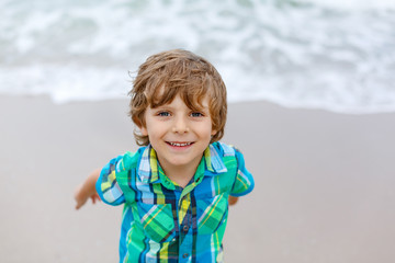 little kid boy running on the beach of ocean