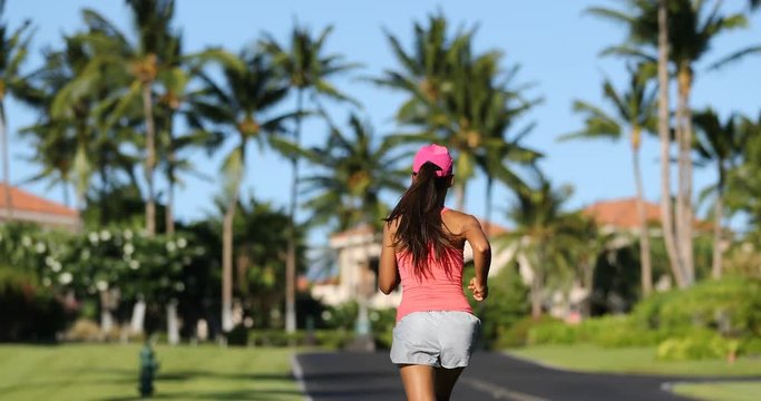 Running woman jogging on road exercising on residential street on summer day. Fit female recreational runner training living healthy active lifestyle. Wellness and sport concept.