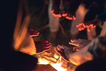 The people warming hands near the bonfire. night time - obrazy, fototapety, plakaty