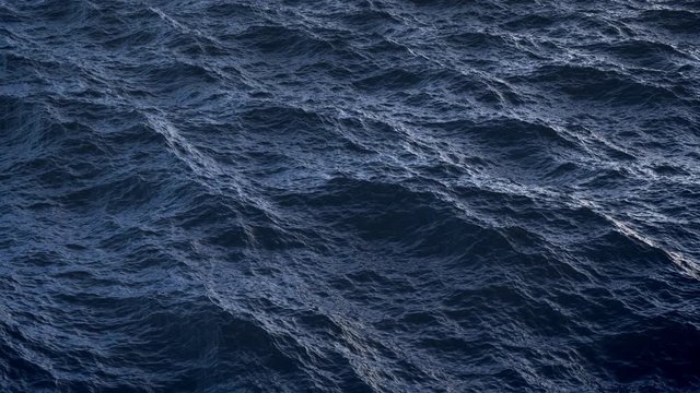 Fly over disturbed ocean water surface in slow motion