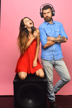 Couple in love sits on the loudspeaker on pink background