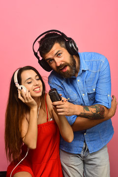 Couple in love holds microphone, sings on pink background
