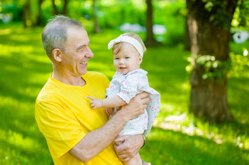 Fototapeta premium Happy grandfather holding a little granddaughter in his arms