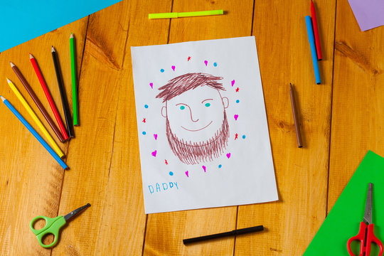 Child draws a portrait of his dad on father's day. The little boy did the drawing with pencil and marker.