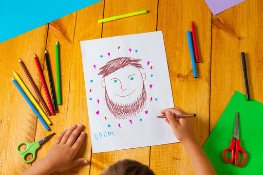 Child draws a portrait of his dad on father's day. The little boy did the drawing with pencil and marker.