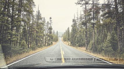 Fototapeta premium Mountain rainy road seen through the windshield, color toning applied, travel concept.