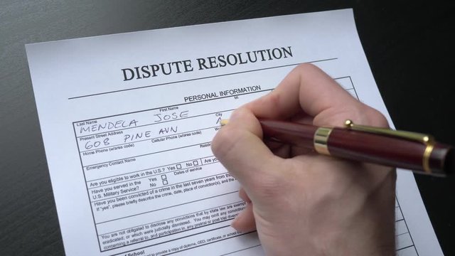 A dispute form being filled by a hand at a desk. This form is randomly filled with no real names or numbers.