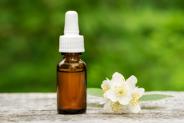 Fototapeta na wymiar Jasmine essential oil in a glass bottle on a wooden table.