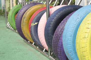 Colorful tires. School field playground. Green artificial grass field, reused rubber wheel...