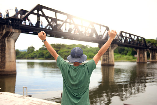 Man is travel in Kanchanaburi and watching the historical bridge on the River Kwai.