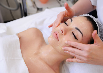Fototapeta na wymiar Beautiful young woman getting a face treatment at beauty salon.