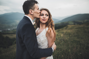 Happy wedding couple posing over beautiful landscape in the mountains