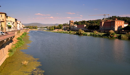 Fototapeta na wymiar Blick auf die idyllische Wohngegend am Ufer des Arno mit Brücke im Hintergrund
