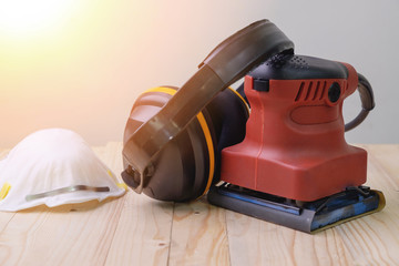 Close up orbital sander machine with protection equipment on wooden.