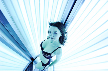 Beautiful young woman preparing for summer in the solarium to get a brown tan
