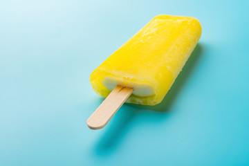 yellow popsicle on a blue background close up