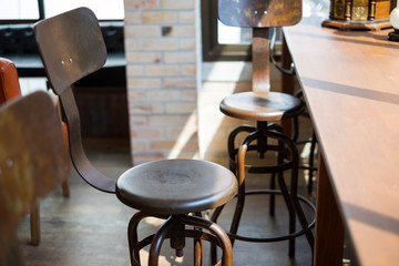 Empty seats and vintage atmosphere of old vintage metal chairs and wooden table top at bar in cafe / coffee shop. Selective blur.