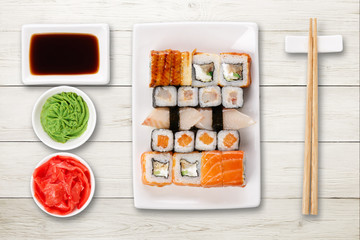Set of sushi, maki and rolls on white wooden background