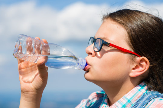 Young girl drinking water outdoors