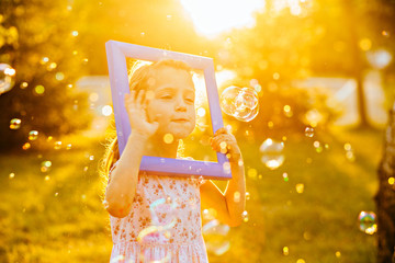 Cute preschooler girl with blue frame on her head playing over grass in sunset in autumn time. Art, drawing and kids creativity concept.