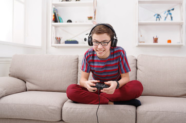 Excited teenage boy playing video game at home