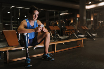 Fototapeta na wymiar Disabled young man using his mobile in the gym.