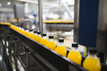 Industrial factory indoors and machinery. Robotic factory line for processing and bottling of soda and orange juice bottles. Selective focus. Short depth of field.