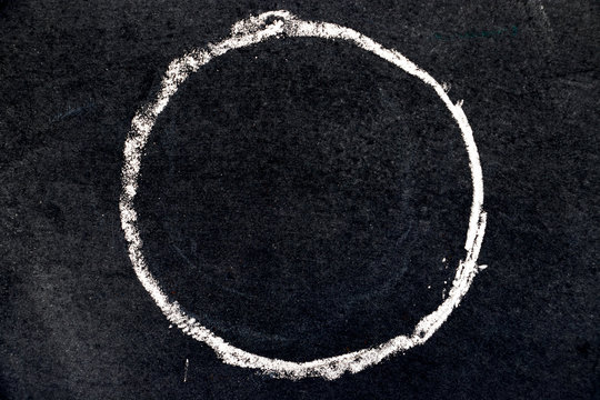 White chalk drawing as circle shape on black board background