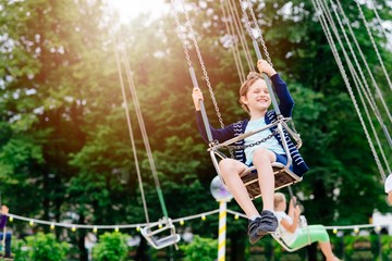 Happy child boy having fun in amusement park.