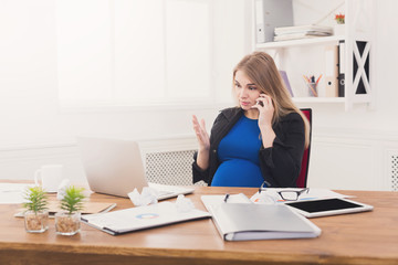 Pregnant business lady at work talking on phone