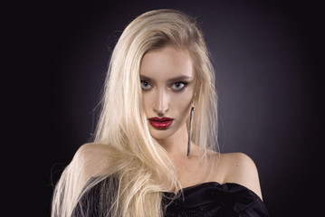 Naklejka premium Beautiful portrait with blonde hair and make up and red lips and jewelry in the studio