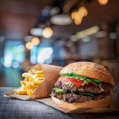 Fresh tasty burger and french fries on wooden table.
