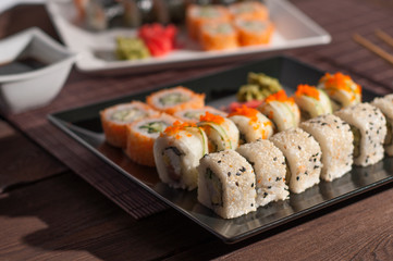 Sushi on a black and white plate, on a wooden mat
