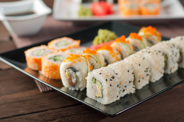 Sushi on a black and white plate, on a wooden mat