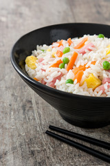 Chinese fried rice with vegetables and omelette on wooden table

