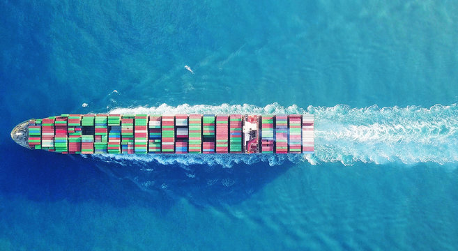 Mega huge fully loaded container ship at sea aerial top down