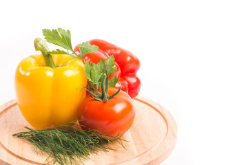 Vegetables, peppers and tomato lie on a wooden kitchen board isolated on a white background