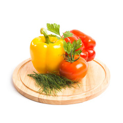 Vegetables, peppers and tomato lie on a wooden kitchen board isolated on a white background