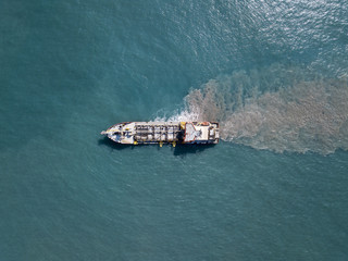 Suction Dredger ship working near the port - with mud, Pollution, brown Muddy water - aerial tip down shot