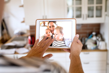 Father at home with tablet, video chatting with his family.