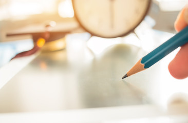 Alarm clock with Graduation cap and optical form of standardized exams or test on touch screen tablet with hand holding blue pencil for examination, Education concept,selective focus,vintage