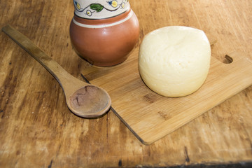 head of cheese gouda sliced piece of jug of milk spoon on  wooden background