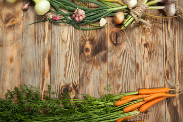 Fresh vegetables, garlic, carrots and onions on a rustic wooden background. View from above.