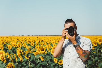 Portrait Of Male Photographer Making Photo With Camera In Hands Outdoors On Sunflowers Field