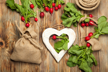 Red radishes in a wooden bowl on old table.