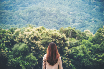 A woman turn back and standing alone with green nature and mountain background