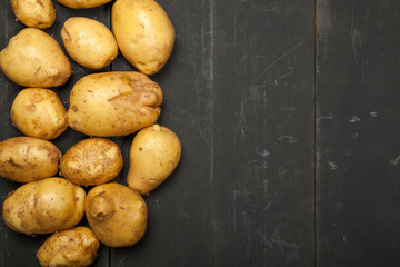 Fresh potatoes on a black wooden background. Rustic style.