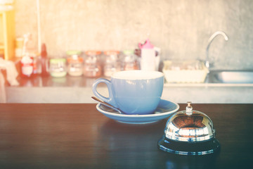 bell and hot coffee cup on coffee shop counter for alert or wark up concept.