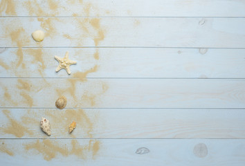Conchas, estrella de mar y caracolas marinos sobre fondo de madera azul con arena